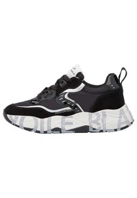Sort og hvid lavtop sneakers med snørelukning, chunkysåle med store grå bogstaver, og en trækstrop ved hælen.