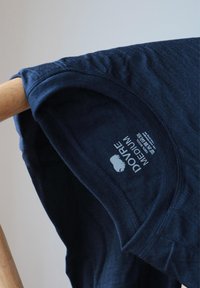 Marineblå T-shirt med rund hals, glat stoftekstur og trykt label, der angiver størrelse "Medium" og mærket "Dovre."