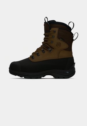 Brun vandtæt vandrestøvle med sort gummisål, snørebåndsdesign, polstret krave og trækstrop. Har metalbeslag og strukturerede detaljer.