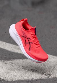 Laufschuh mit einem leuchtend pinken Obermaterial, strukturierten Oberflächen, schwarzen Akzenten und einer weißen Zwischensohle. Leichtes Design für optimale Leistung.