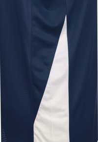 Pantaloni sportivi blu navy con una texture liscia, caratterizzati da pannelli laterali bianchi e piccole perforazioni per la traspirabilità. Design semplice, senza pattern.
