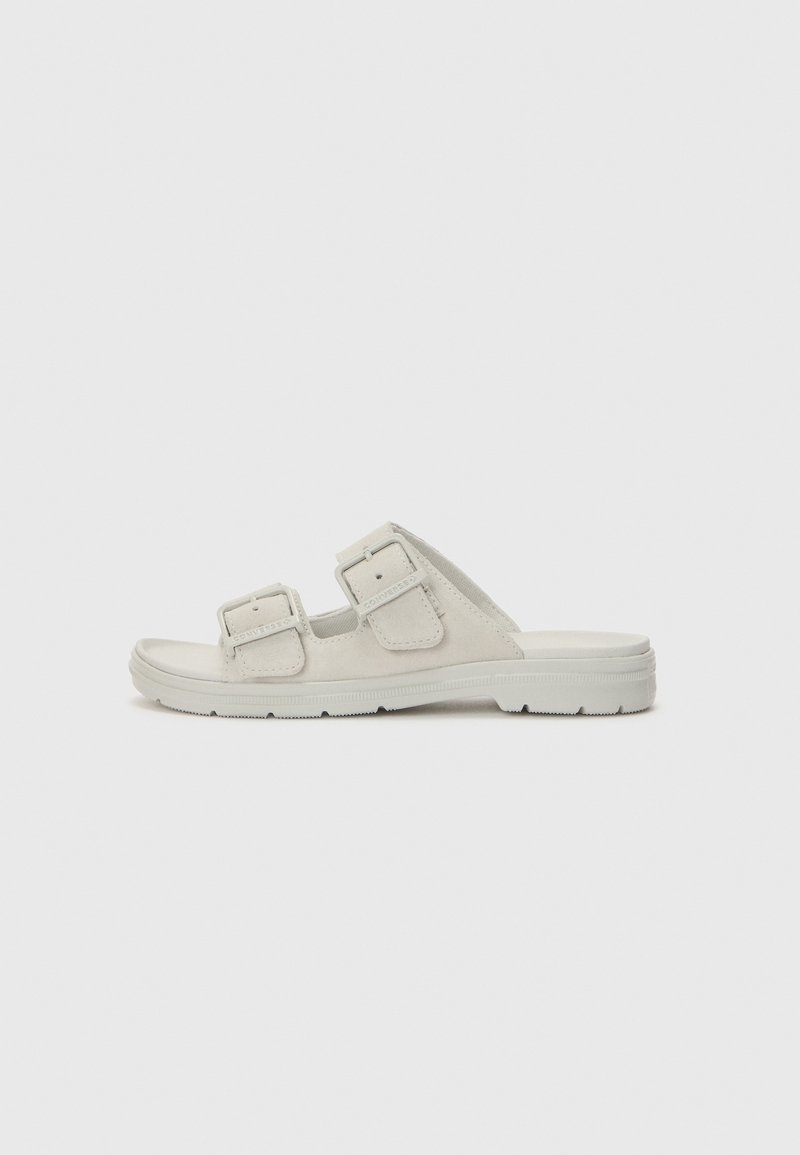 Lys grå sandal med doble justerbare stropper, flat såle, mykt materiale, minimalistisk design og ingen synlige utsmykninger.