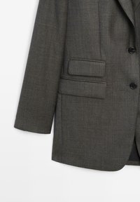 Gray tailored blazer with a textured fabric, single button closure, and a patch pocket. Features a notched lapel and structured fit.