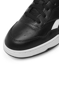 Čierne kožené tenisky s hladkou textúrou, perforovanou špičkou a bielou gumovou podrážkou. Šnurovací dizajn s kontrastnými bielymi akcentmi.