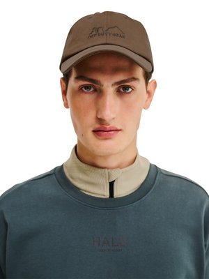 Young man wearing a brown cap labeled "Off Duty Gear," beige zip-up collar, and blue sweatshirt with "HALO" printed on the chest.