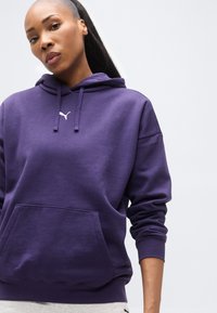 Μωβ φούτερ με κουκούλα και τσέπη τύπου καγκουρό, με ριμπ μανσέτες και τελείωμα. Διαθέτει μικρό λευκό λογότυπο στο στήθος. Μαλακό, υφασμάτινο υλικό με υφή.