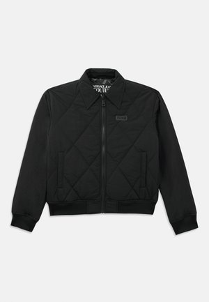Black quilted jacket featuring a zip front, collar, and ribbed cuffs. A small logo patch is visible on the chest. Smooth fabric texture.