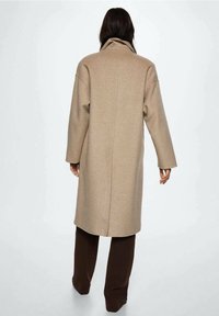 Beige mantel van een wolmengsel met een hoge kraag, verlaagde schouders en een losse pasvorm, voorzien van een naad in het midden van de rug en lange mouwen.