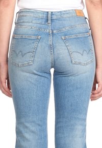 Helle blaue High-Waist-Jeans mit einer glatten Textur, ausgestattet mit Gesäßtaschen und einem genähten Design, das einem Wellenmuster ähnelt.