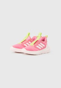 Scarpe da ginnastica rosa con suole bianche, strisce bianche sui lati e linguette neon gialle in cima e sul retro, su sfondo uniforme.