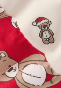 Tessuto rosso e bianco con un design di orso. L'orso indossa un cappello di Babbo Natale rosso, con dettagli marroni e bianchi sul corpo. Texture morbida.