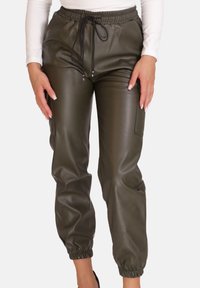 Jogginghosen aus olivgrünem Kunstleder mit elastischem Bund, Kordelzug, Seitentaschen und gerafften Bündchen an den Knöcheln. Glatte Textur.