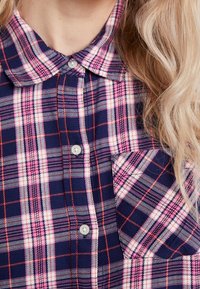 Knapp-up skjorta i marinblå med rosa och vit rutmönster. Har en krage och en bröstficka. Tillverkad av ett mjukt tyg med en strukturerad väv.