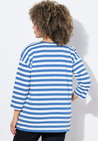 Blau und weiß gestreiftes Langarmhemd mit lockerer Passform und rundem Ausschnitt; der Stoff wirkt weich mit einer glatten Textur.