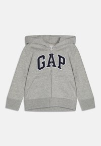 Sudadera gris con cremallera, hecha de una tela suave, que cuenta con una capucha, dos bolsillos frontales y una llamativa letra "GAP" en azul marino en el pecho.