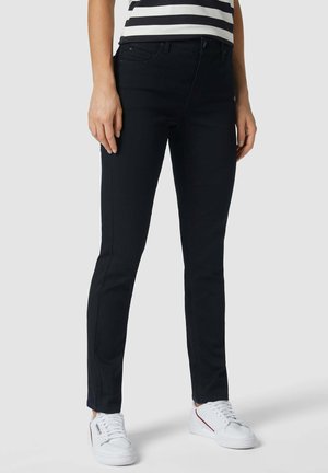 Zwarte stretchjeans met een slim fit, voorzien van een klassieke vijf-pocketontwerp en subtiele stikdetails, gecombineerd met witte sneakers.