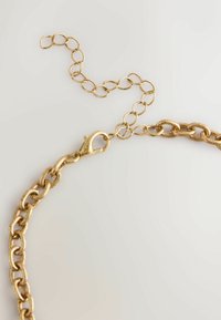 Goldene Metallkette mit großen, verbundenen ovalen Formen und einem Karabinerhaken, ausgestattet mit einer verstellbaren Verlängerungskette.