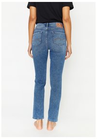 Jeans in denim blu con gamba dritta, lavaggio medio, cuciture a contrasto e due tasche posteriori. Etichetta del marchio visibile sulla vita.