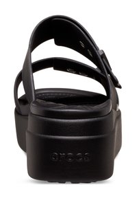 Black platform sandals featuring multiple straps, a textured footbed, and a logo on the side. Made from durable synthetic material.