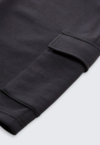 Donkergrijze stoffen manchet met een gestructureerde afwerking en ribbeldetail. De manchet is gevouwen en toont een gladde rand en stiknaad.