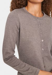 Langarm cardigan van een zachte, gestructureerde bruine stof, met een ronde halslijn en vijf bijpassende knopen aan de voorkant.