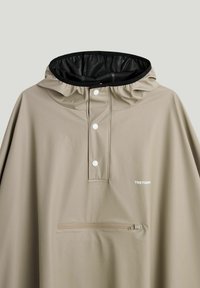 Beige vandtæt regnponcho med sort foret hætte, frontknapper med trykknapper, vandret lynlåslomme og "TRETORN" logo på brystet.