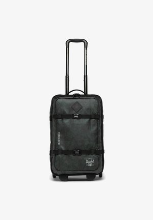 Valise à roulettes noire et verte avec une surface texturée, une poignée réglable, deux sangles de sécurité et des détails de taille imprimés sur le côté.