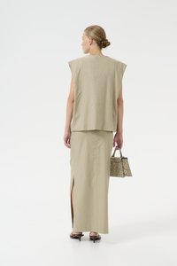 Top beige in misto lino con maniche corte larghe e una gonna lunga coordinata con uno spacco laterale, abbinato a una borsa a tracolla con motivo.