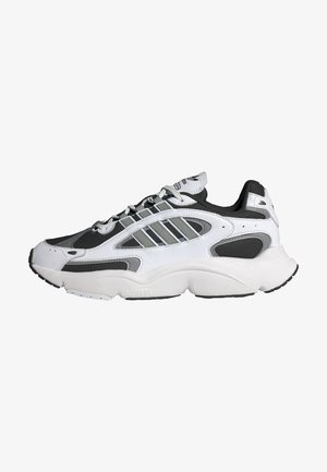 Biało-czarny sportowy sneaker z szarymi paskami, zapinany na sznurowadła, z grubą, amortyzowaną podeszwą, pokazany z profilu bocznego, skierowany w lewo.