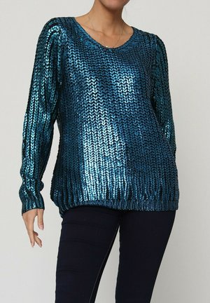 Pull en teal pailleté avec un col en V, coupe ample, et des poignets et ourlet côtelés. Présente un motif texturé et une finition brillante.