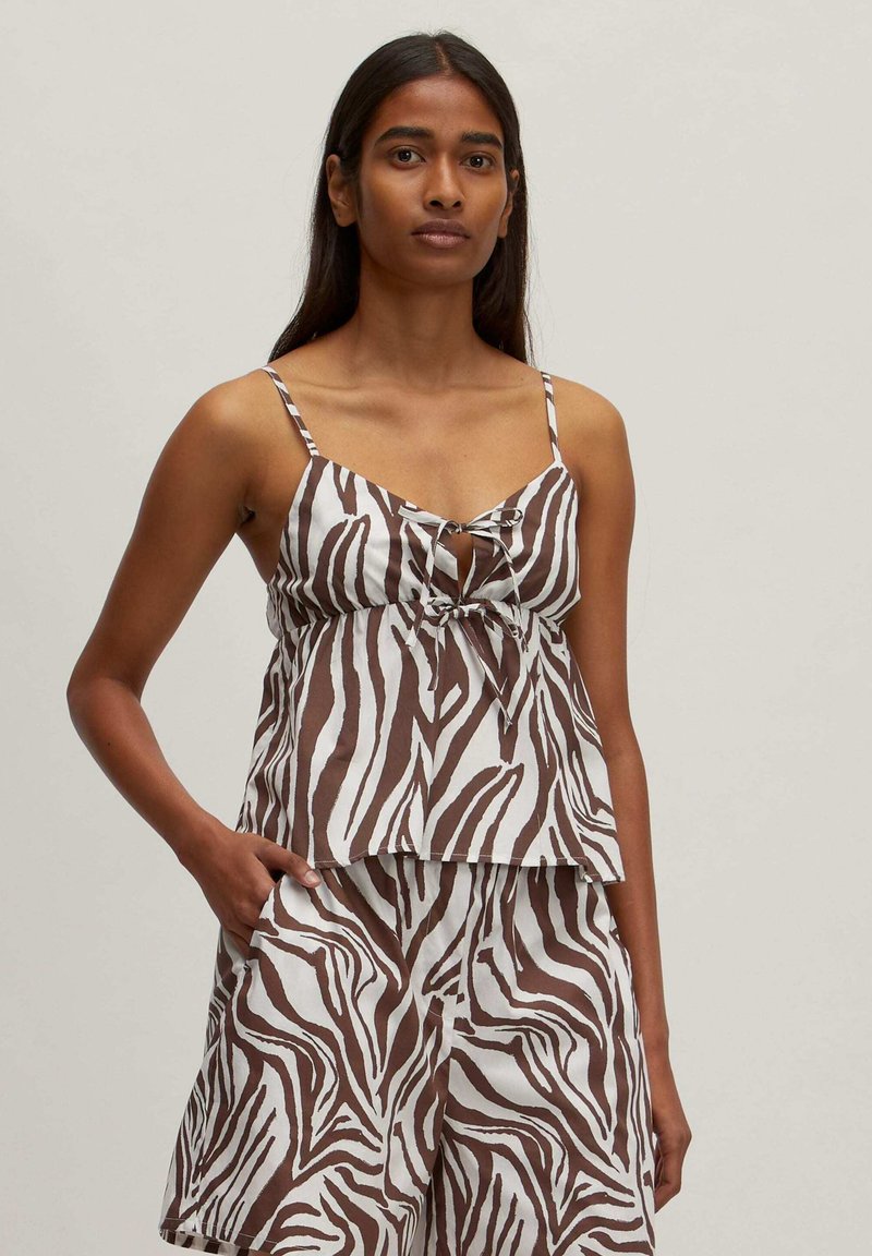 Bruin en wit zebra-streep top met spaghettibandjes en een strikdetail aan de voorkant, gecombineerd met bijpassende shorts. Katoenen stof.