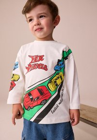 Biely dlhý rukáv tričko s farebnými grafikami áut v modrej, červenej, žltej a zelenej farbe so textom "Hot Wheels" a designovými prvkami s pretekárskou tematikou.