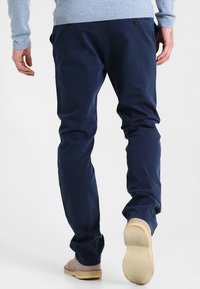 Navy blue trousers with a straight fit, made of cotton. Features a waistband button, subtle pockets, and a smooth texture.