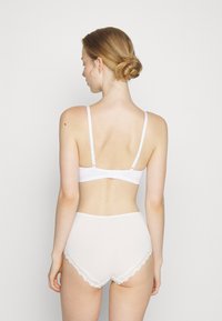 Sutiã branco com alças ajustáveis e fecho de gancho, combinado com roupa interior branca de cintura alta com renda nas bordas.