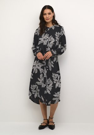 Langes schwarzes Kleid mit weißem Blattmuster, durchgehender Knopfleiste, langen Ärmeln und einem lockeren Schnitt. Weicher Stoff mit glatter Textur.