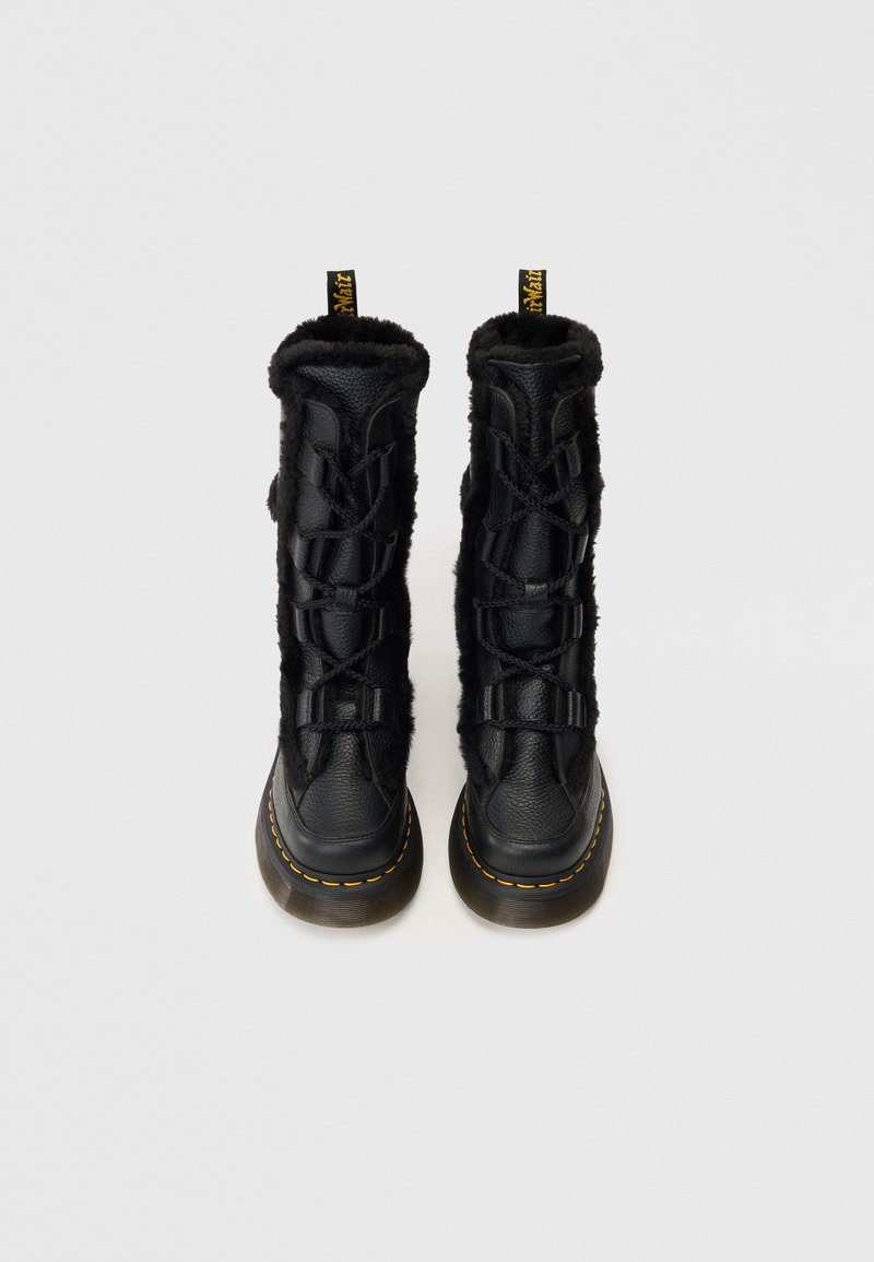 Bottes en cuir noir à lacets avec un extérieur en cuir texturé, doublure en fourrure noire duveteuse, bout rond et détails de couture jaune sur la semelle.