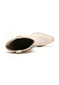 Botín de tobillo de ante beige con puntera afilada y textura suave, que cuenta con una lengüeta redonda para facilitar el calzado y un diseño minimalista.