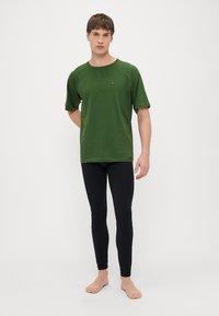 Πράσινο κοντομάνικο t-shirt από μαλακό ύφασμα, σε συνδυασμό με μαύρο κολάν. Το t-shirt έχει απλό σχέδιο και μικρό λογότυπο στο στήθος.