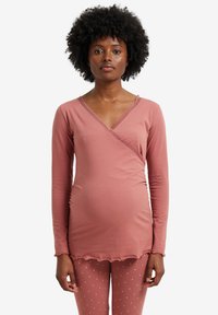 Long-sleeve, wrap-style top in dusty rose, made of soft cotton, featuring lace trim and a gathered detail on the side. Paired with polka-dot leggings.