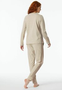 Beige Loungewear-Set mit langärmligem Oberteil und passenden Hosen mit einem gerippten seitlichen Einsatz, hergestellt aus weichem Stoff.