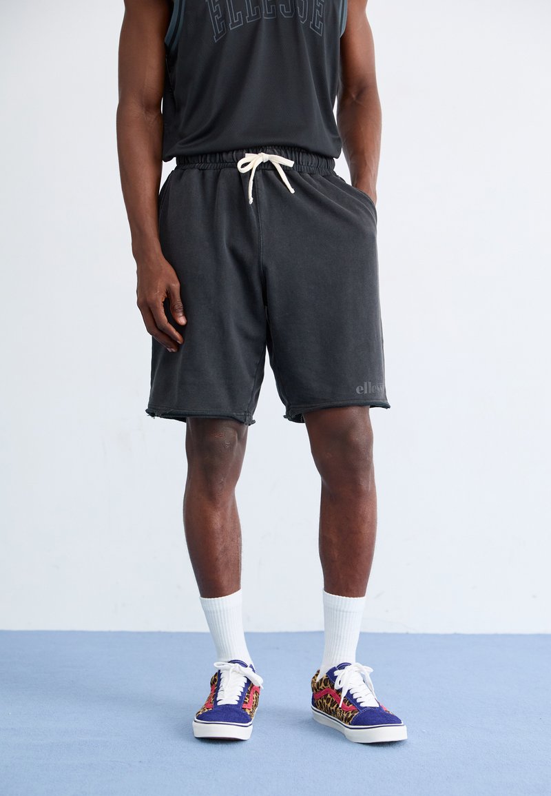 Svart bomullsshorts med elastisk midjebånd og snøring. Kombiner med fargerike joggesko med et livlig mønster og hvite sokker.