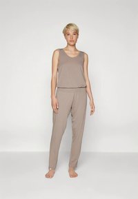 Svetlo rjav top brez rokavov in ujemajoče se sproščene hlače iz mehke tkanine. Top ima okrogel izrez; hlače imajo elastičen pas.