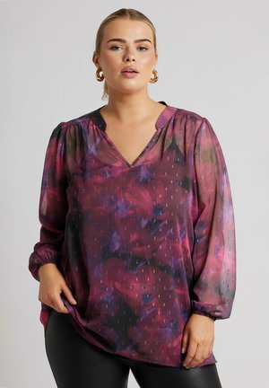 Transparante blouse met bloemenpatroon in tinten paars en roze, met lange mouwen en elastische manchetten en een V-hals.