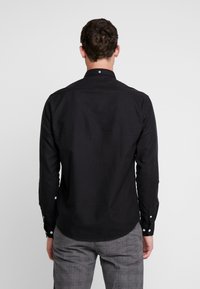 Zwarte longsleeve shirt met een button-down kraag, gladde textuur en een ronde zoom, met knoopmanchetten.