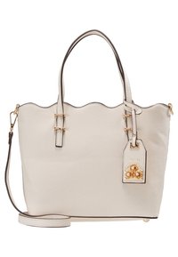 Beige synthetic tote bag with scalloped top edge, dual handles, and adjustable shoulder strap. Features a decorative charm with gold accents.