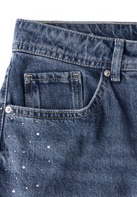 Jeans z denimu w średnim niebieskim kolorze o teksturowanym wykończeniu. Posiada małą kieszonkę z przodu oraz rozrzucone srebrne ćwieki na boku jako detal.