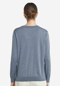 Ljusblå pullovertröja i mjukt material, med långa ärmar, rund halsringning och ribbade detaljer vid ärmsluten och nederkanten.