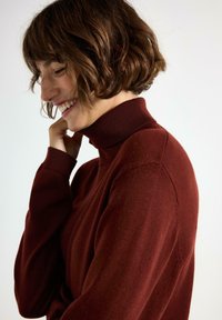 Burgundin turtleneck-svettari pehmeästä neuleesta, jossa on ribbireunat hihansuissa ja kauluksessa, slim fit -muotoilu ja hienovarainen tekstuuri.