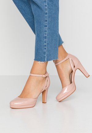 Różowe lakierowane szpilki z okrągłym noskiem, paskiem wokół kostki i gładką powierzchnią. Niskie boki i stożkowy obcas dla wsparcia.