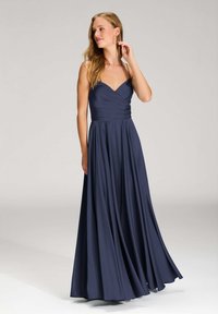 Langes marineblaues Kleid mit tailliertem Oberteil, V-Ausschnitt und dünnen Trägern. Der Rock fließt elegant und ist aus einem glatten, fallenden Stoff gefertigt.